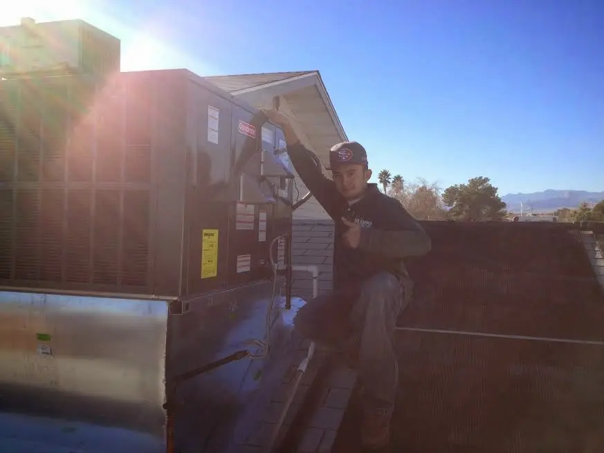 HVAC technician performing Air Duct Repair on a rooftop unit in Shirley